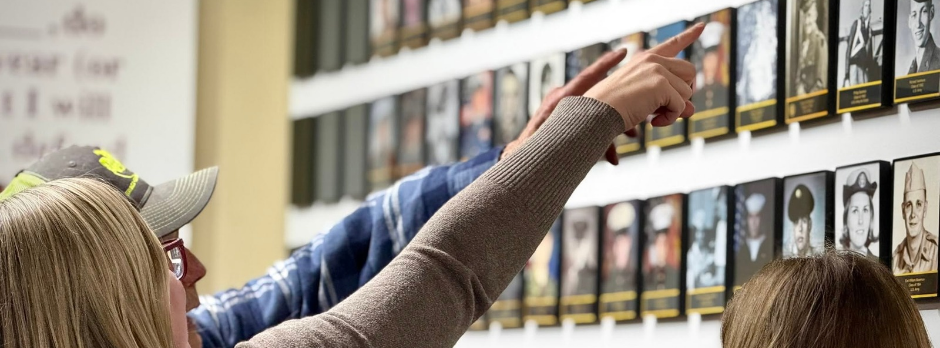 Visitors point to photographs displayed on the Coopersville High School Wall of Honor.