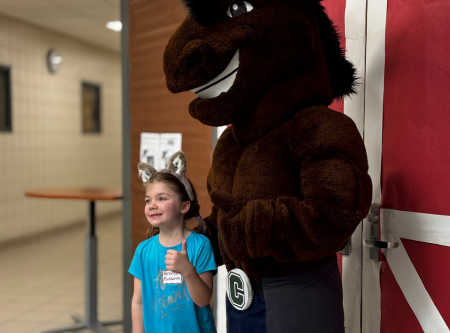 Student smiling with brown bronco mascot giving thumbs up